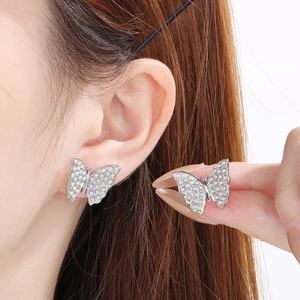 Detail of silver titanium steel butterfly earrings with white pearl inlay on model