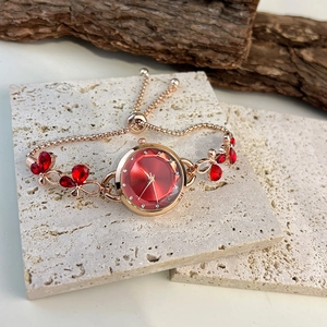 Detail of rose gold butterfly watch with red dial and crystal charms on stone base