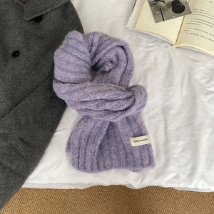 Detailed texture of a soft purple knitted wool scarf with a small woven brand label