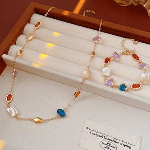 Détail d'un ensemble bijoux vintage en coquillage avec chaîne dorée et pierres colorées
