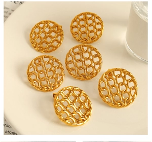 Detailed close-up of golden hollow circular stud earrings with woven metallic texture