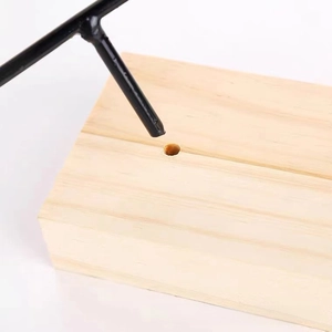 Macro detail of black metal T-bar and solid wood base assembly for jewelry display