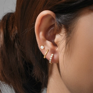 Close-up of gold 925 silver hoop earrings set with opal stones on a female ear