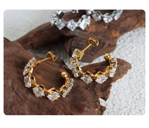 Macro shot of C-shaped 18K gold plated earrings with sparkling square cubic zirconia stones
