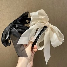 Detail showing oversized organza bow hair clips in black and creamy white colors