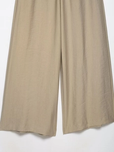 Detailed close-up of khaki wide-leg trousers showing breathable linen texture and drape