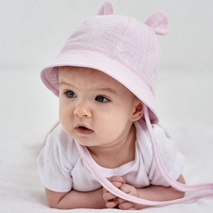 Pink cotton baby bucket hat with cute ears and chin strap worn by a baby on soft fabric