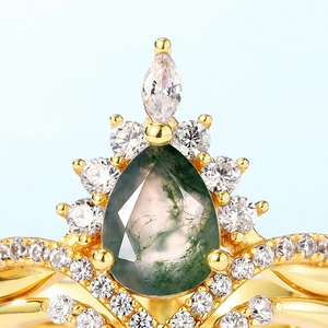 Pear cut moss agate crown ring in gold with round and marquise diamonds on blue background