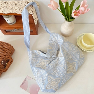 Détail du sac hobo bleu clair avec broderie de dentelle papillon blanche complexe