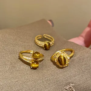 Vista dettagliata di tre anelli placcati in oro con occhio di tigre e zirconi