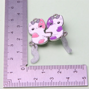 Detailed view of cat heart pendants showing size measurement on a centimeter ruler