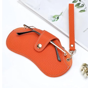 Portable orange pebbled leather glasses pouch with neck strap and gold snap closure