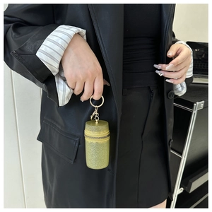 Close-up of a mini semi-transparent green glitter cylinder pouch with gold keychain