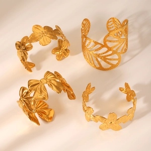 Dettaglio di bracciali rigidi in acciaio inossidabile dorato 18K con motivi di foglie e fiori