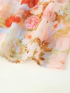 Detail of floral chiffon fabric with orange and green prints and delicate hem stitching