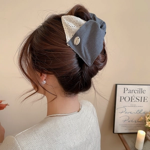 Vue détaillée d'une grande pince à cheveux nœud avec dentelle et broderie sur les cheveux