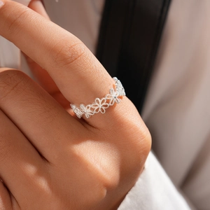 Detailed view of a silver floral hollow ring featuring zircon on a model's hand