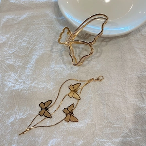 Close-up of golden metal butterfly hair claw and fringe pendant on beige fabric