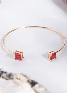 Macro shot of gold-plated open bracelet featuring dual square-cut red zircon stones