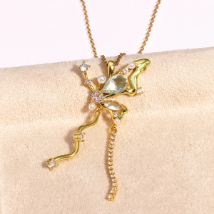 Vue macro du pendentif fleur dorée avec zircons et perles sur velours beige doux