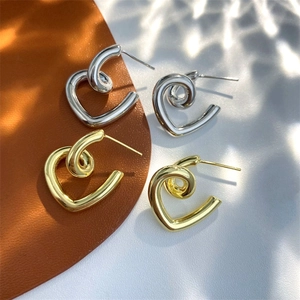 Detailed view of polished gold and silver heart earrings on a leather texture background