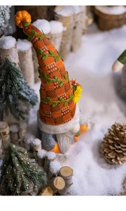Detail of a festive gnome doll with an orange plaid hat and faux fur beard in a snowy forest