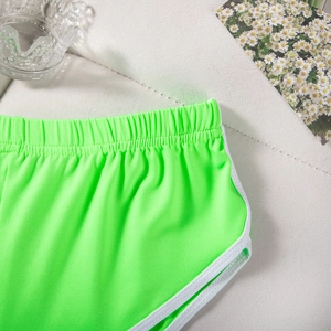 Detail der neongrünen Sportshorts mit elastischem Bund und weißer Kontrastpaspelierung