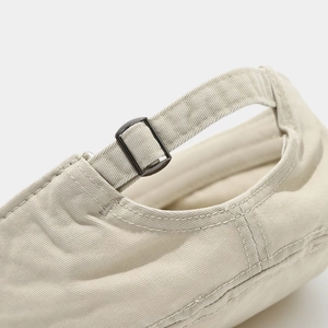 Detail view of adjustable back strap and matte black metal buckle on beige canvas hat