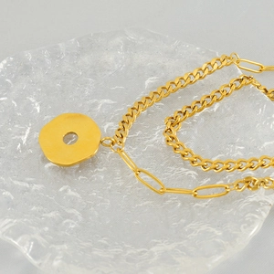 Modern double-layered gold stainless steel necklace with daisy pendant on a tray