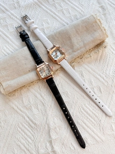 Top view of square rose gold ladies watches with black and white leather straps on fabric
