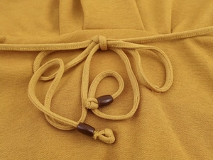Vista dettagliata del tessuto a maglia giallo senape con coulisse e perline marroni