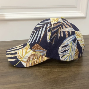 Navy blue baseball cap with tropical palm leaf print on a vintage wood tabletop