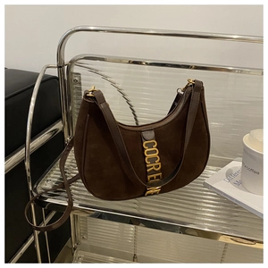 Detail of dark brown suede crescent bag with gold logo on a silver display stand