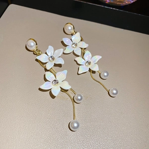 Detailed view of gold tassel earrings with pearl beads and shimmering flower petals