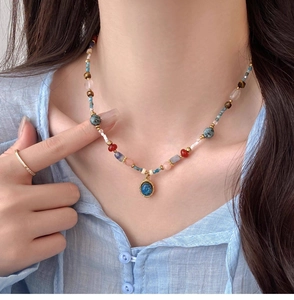 Détail d'un collier en perles de pierre colorées avec pendentif ovale bleu vintage