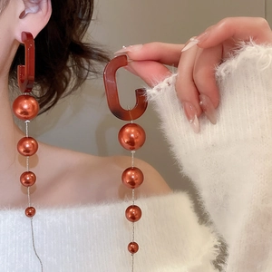 Close-up of vintage long fringe earrings with oval resin hooks and gradient pearls