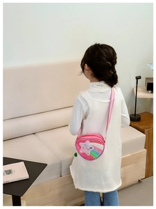 Fillette portant un sac bandoulière cœur à paillettes avec sangle arc-en-ciel en intérieur