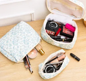Three-piece light blue floral quilted cotton makeup bag set on a wooden surface