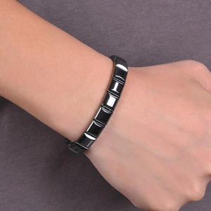 Close-up of a wide black magnetic hematite bracelet worn on a wrist for men