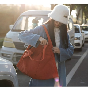 Close-up of a large red canvas tote bag shown in a casual outdoor street setting