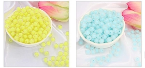Close-up of translucent yellow and light blue acrylic beads on elegant white silk fabric