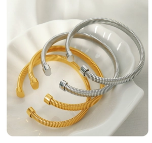 Close-up of gold and silver elastic snake bone bracelets in a white shell dish
