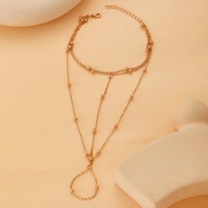 Detail view of a bohemian gold beaded barefoot sandal chain for beach vacations