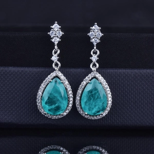 Detail of luxury teardrop Paraiba blue gemstone earrings with diamond halo and silver setting