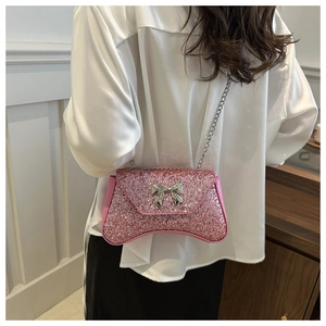 Chic pink glitter shoulder bag with silver bow clasp and chain strap on a model