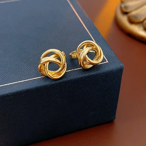 Vue macro de boucles d'oreilles créoles torsadées dorées sur un écrin