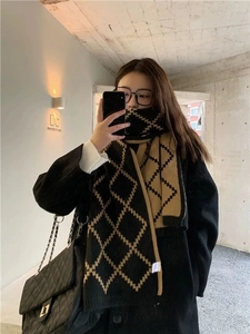 Close-up of stylish black and camel geometric knit scarf styled with a black coat