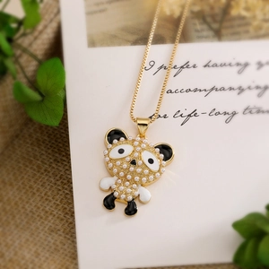 Gros plan d'un pendentif panda doré avec perles blanches sur une carte cadeau