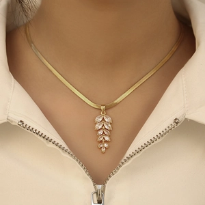 Elegant gold snake chain necklace with wheat-shaped cubic zirconia pendant on a female model