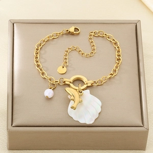 Detail view of gold stainless steel bracelet featuring shell, dolphin and pearl charms